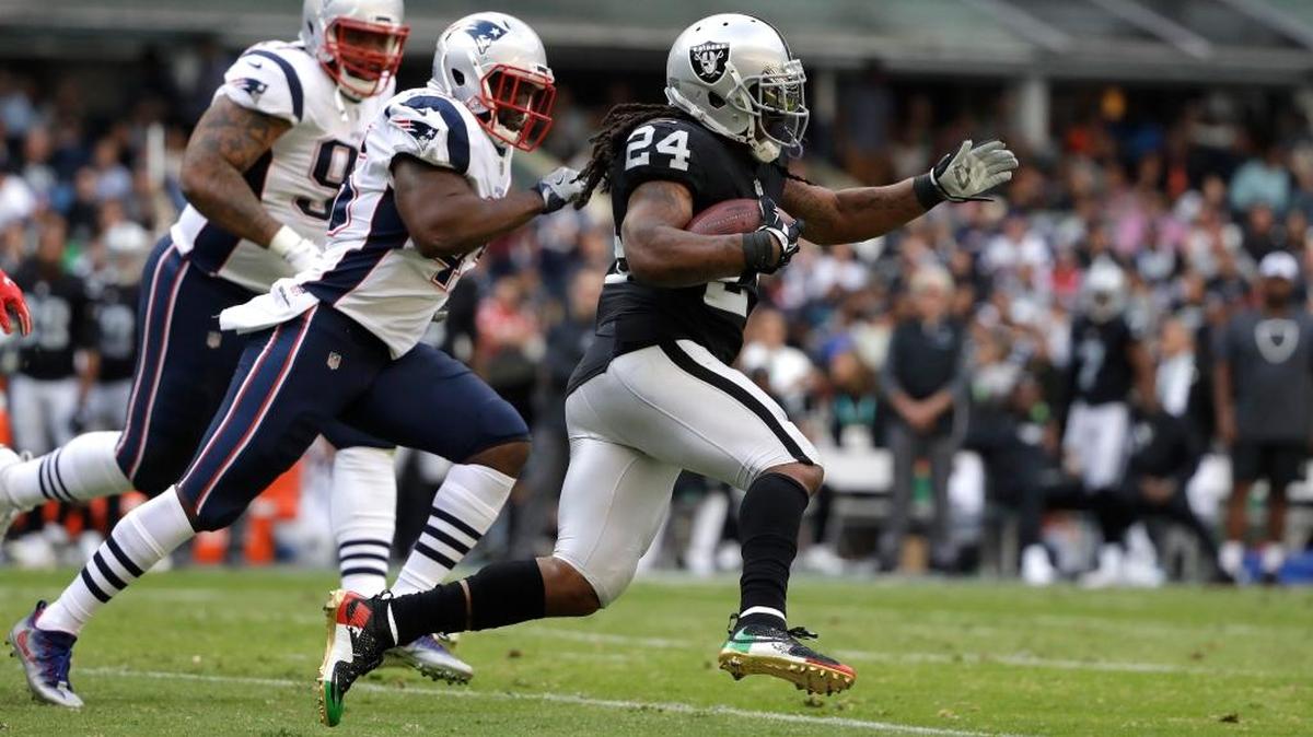 Raiders running back Marshawn Lynch (24) rushes past New England Patriots linebacker David Harris, center, Sunday in Mexico City.