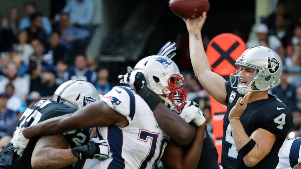Raiders quarterback Derek Carr, right, passes against the New England Patriots on Nov. 19 in Mexico City.