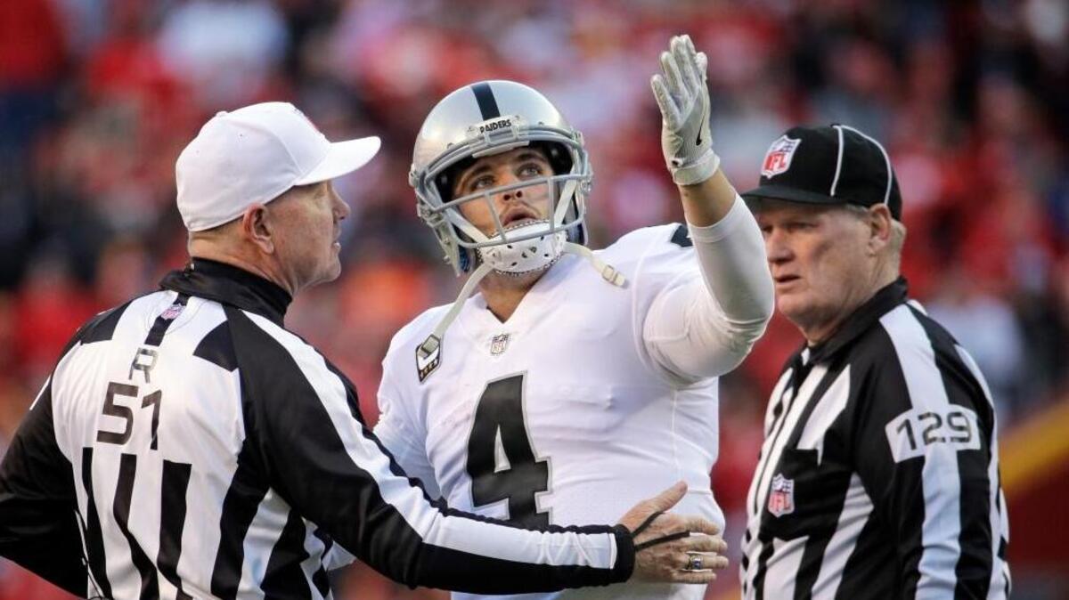 Oakland Raiders quarterback Derek Carr has words with referee Carl Cheffers, left, and umpire Bill Schuster while playing the Kansas City Chiefs in on Dec. 10.