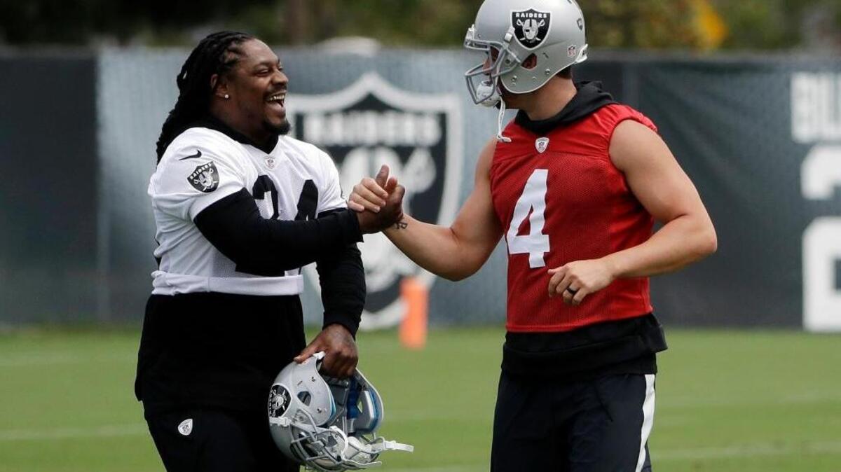 Oakland Raiders running back Marshawn Lynch, left, shakes hands with quarterback Derek Carr during the team's organized team activity at its NFL football training facility Tuesday, May 30, 2017, in Alameda, Calif.