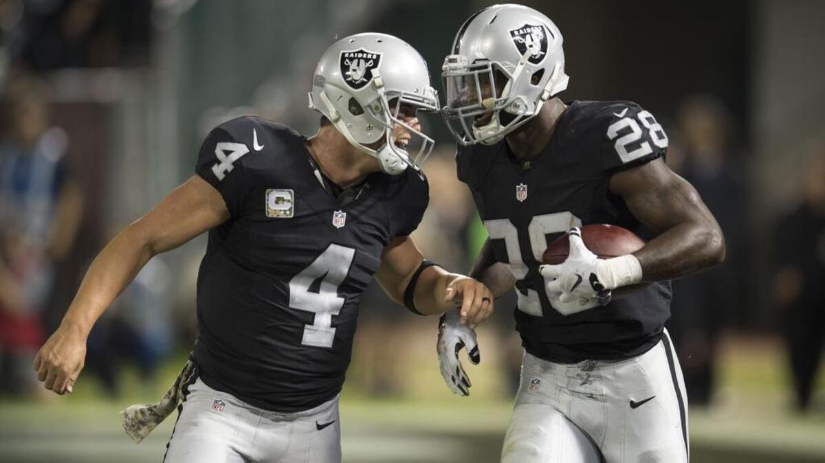 Oakland Raiders quarterback Derek Carr (4) celebrates a touchdown with teammate Oakland Raiders running back Latavius Murray (28) against the Denver Broncos at Oaklanda-Alameda County Coliseum on Sunday, November 6, 2016.