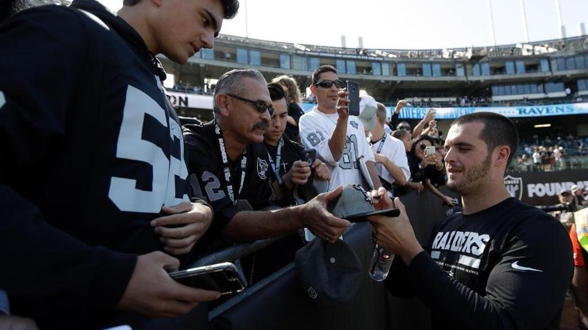 Raiders quarterback Derek Carr, right, signs autographs for fans before a game against the Baltimore Ravens on Oct. 8 in Oakland. Carr missed that game with a back injury but is expected to play Sunday against the Los Angeles Chargers.