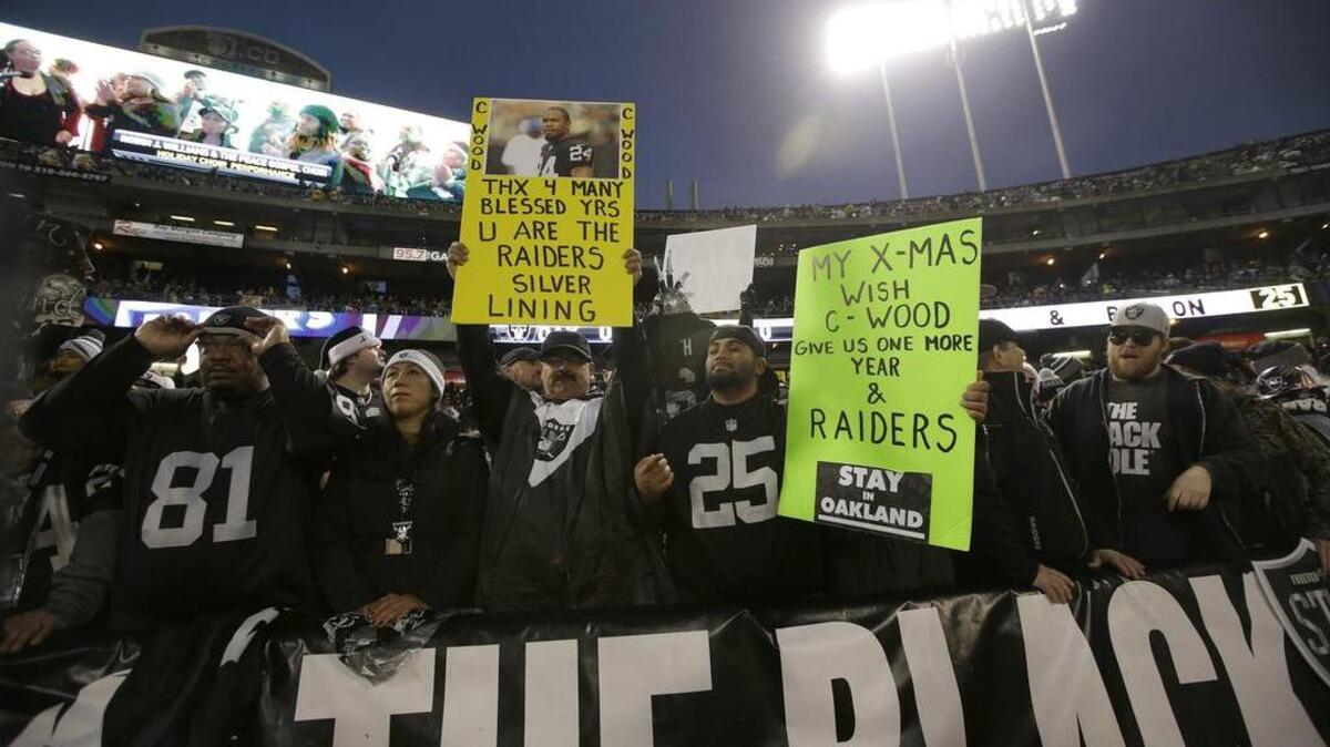 Fans hold up signs for retiring Raiders cornerback Charles Woodson and for the Raiders to stay in Oakland during the first half against San Diego in Oakland, Calif., Thursday, Dec. 24, 2015.