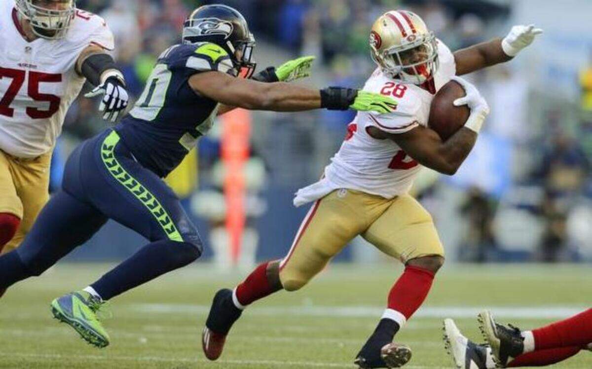 
San Francisco 49ers running back Carlos Hyde (28) tries to avoid a tackle by Seattle Seahawks outside linebacker K.J. Wright, left, in the first half of an NFL football game, Sunday, Dec. 14, 2014, in Seattle.
