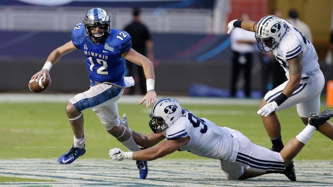 Brigham Young linebacker Bronson Kaufusi, center, and defensive lineman Tomasi Laulile, right, attempt to tackle Memphis quarterback Paxton Lynch (12) during the second half of the in the inaugural Miami Beach Bowl football game, Monday, Dec. 22, 2014 in Miami. Memphis defeated Brigham Young 55-48 in double overtime.