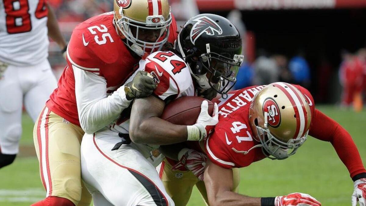 Atlanta Falcons running back Devonta Freeman (24) is tackled by San Francisco 49ers strong safety Jimmie Ward (25) and defensive back Marcus Cromartie (47) during the first half of an NFL football game in Santa Clara, Calif., Sunday, Nov. 8, 2015.