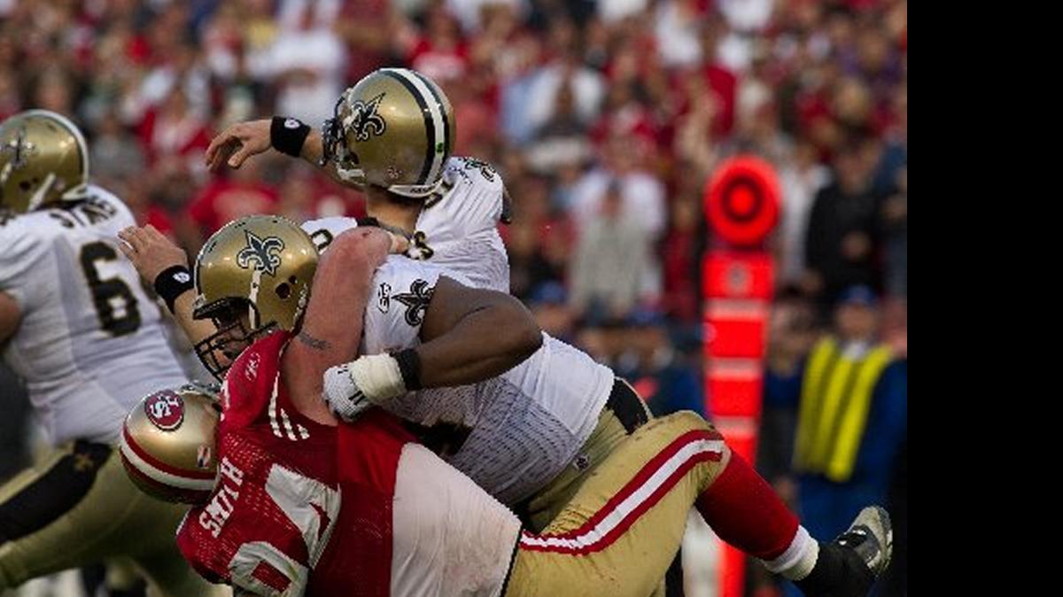 
Justin Smith takes down Saints quarterback Drew Brees – along with New Oleans’ left tackle – in the 2011 divisional playoffs. Smith is considering retirement, and he could decide Friday.
