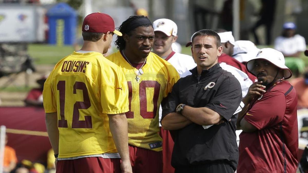 Washington Redskins quarterback coach Matt LaFleur, right, talks with quarterbacks Robert Griffin III, center, and Kirk Cousins (12) on the field as they begin their training camp at the NFL football teams new practice facility in Richmond, Va. Thursday, July 25, 2013.