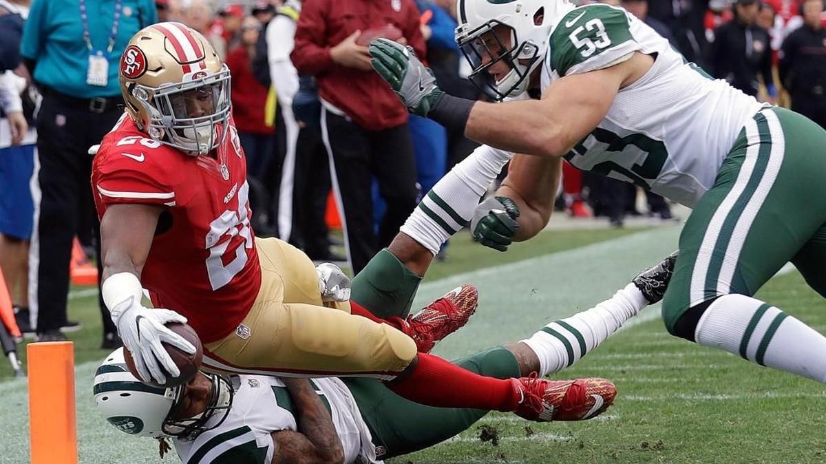 San Francisco 49ers running back Carlos Hyde (28) scores a touchdown against New York Jets defensive back Buster Skrine, bottom, and outside linebacker Mike Catapano (53) during the first half of an NFL football game in Santa Clara, Calif., Sunday, Dec. 11, 2016.