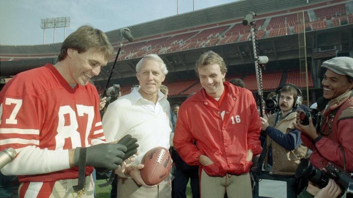 49ers head coach Bill Walsh, center, shares a laugh with quarterback Joe Montana, in red jacket, and receiver Dwight Clark, left, at Candlestick Park on Jan. 16, 1985.