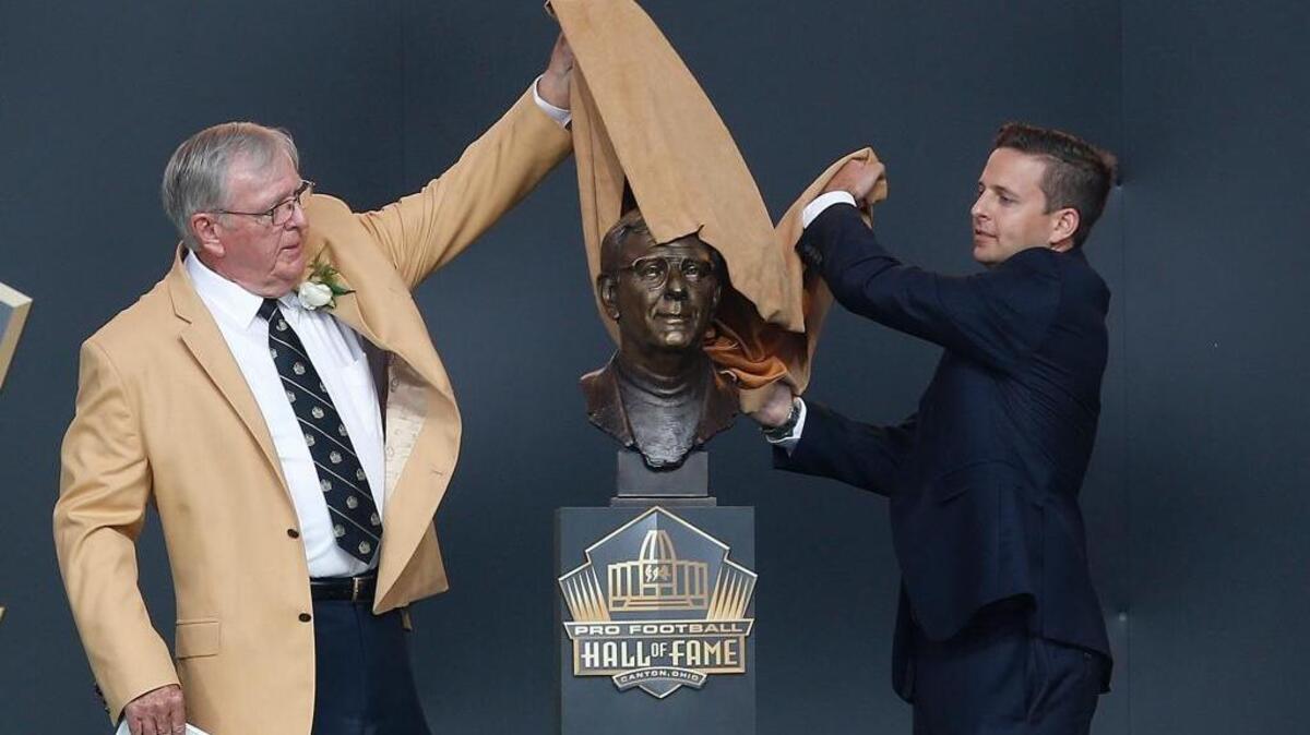 Former NFL contributor Ron Wolf, left, unveils a bust of himself with presenter, son, Eliot Wolf, during an induction ceremony at the Pro Football Hall of Fame, Saturday, Aug. 8, 2015 in Canton, Ohio.