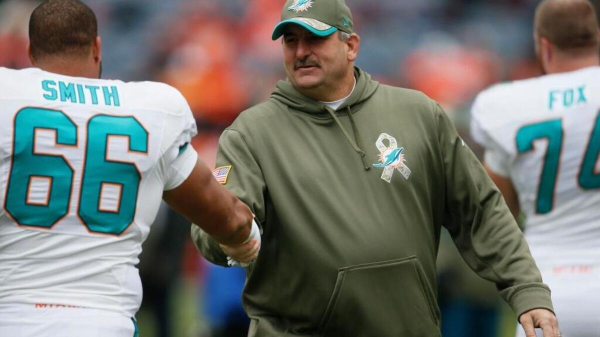 Miami Dolphins offensive line coach John Benton greets Dolphins guard Shelley Smith (66) prior to an NFL football game against the Denver Broncos, Sunday, Nov. 23, 2014, in Denver.