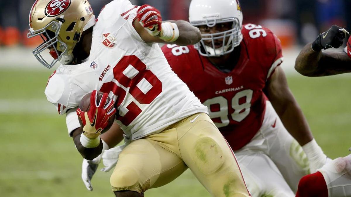 San Francisco 49ers running back Carlos Hyde (28) eludes the hit of Arizona Cardinals nose tackle Corey Peters (98) during the first half of an NFL football game, Sunday, Nov. 13, 2016, in Glendale, Ariz.