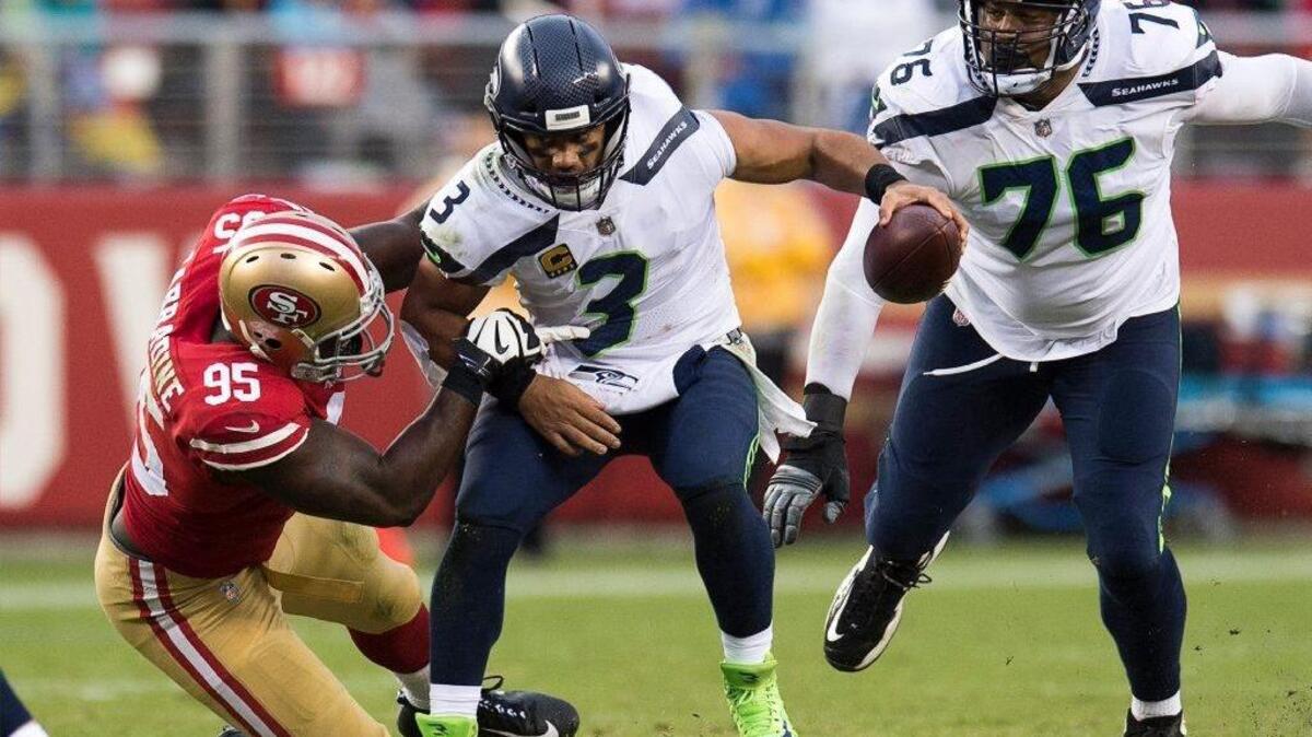 Seattle Seahawks quarterback Russell Wilson eludes 49ers defensive end Tank Carradine on Sunday at Levi’s Stadium.