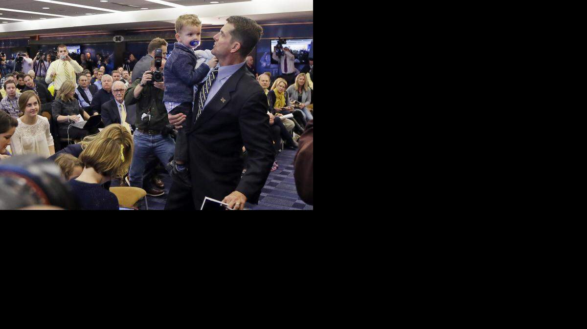 
Jim Harbaugh holds his son Jack after being introduced as the new head coach at Michigan during an NCAA college football news conference Tuesday, Dec. 30, 2014, in Ann Arbor, Mich.
