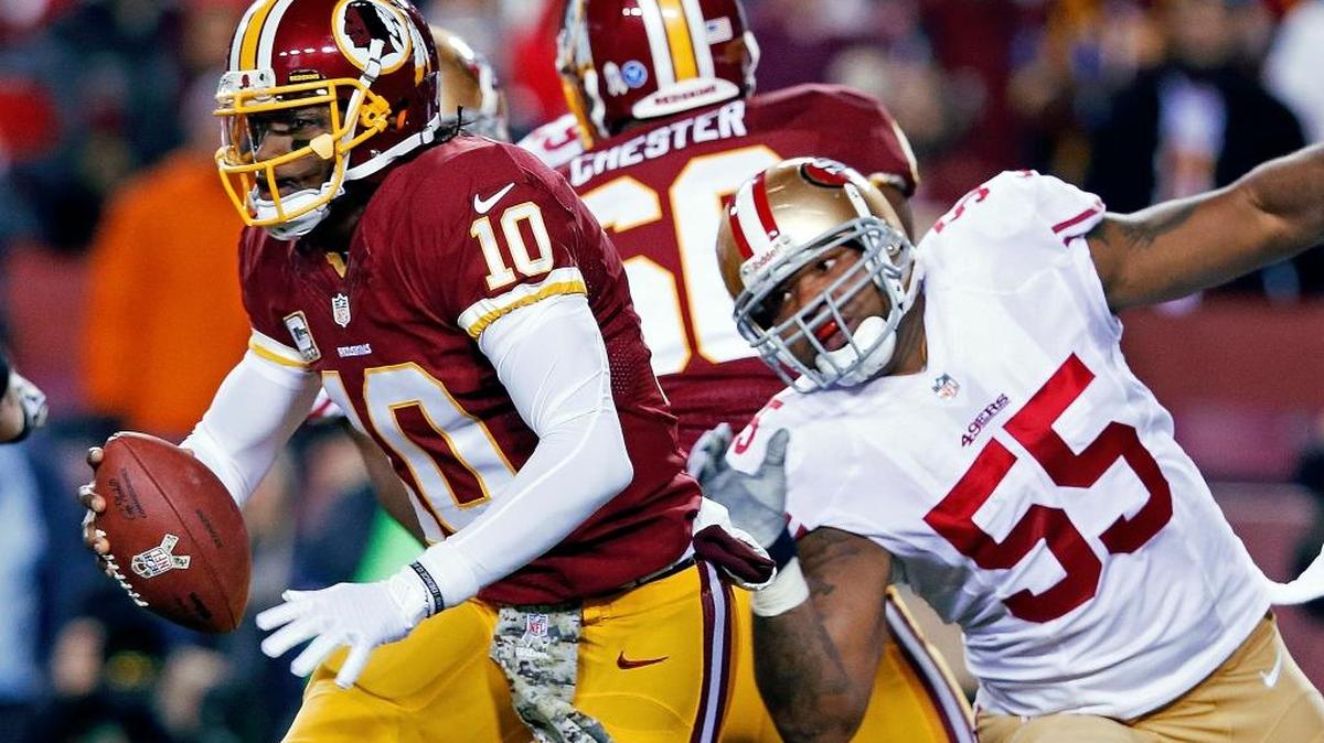 Washington Redskins quarterback Robert Griffin III scrambles away from San Francisco 49ers outside linebacker Ahmad Brooks during the first half of an NFL football game in Landover, Md., Monday, Nov. 25, 2013.