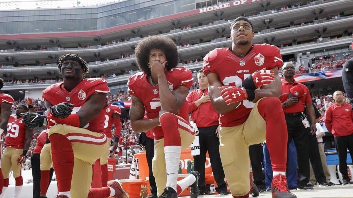 Eli Harold, Colin Kaepernick, center, and Eric Reid kneel during the national anthem before an NFL football game against the Dallas Cowboys in Santa Clara, Calif. What started as a protest against police brutality has mushroomed a year later into a divisive debate over the future of Kaepernick who refused to stand for the national anthem and now faces what his fans see as blackballing for speaking out in a country roiled by racial strife. The once-rising star and Super Bowl quarterback has been unemployed since March, when he opted out of his contract and became a free agent who could sign with any team.