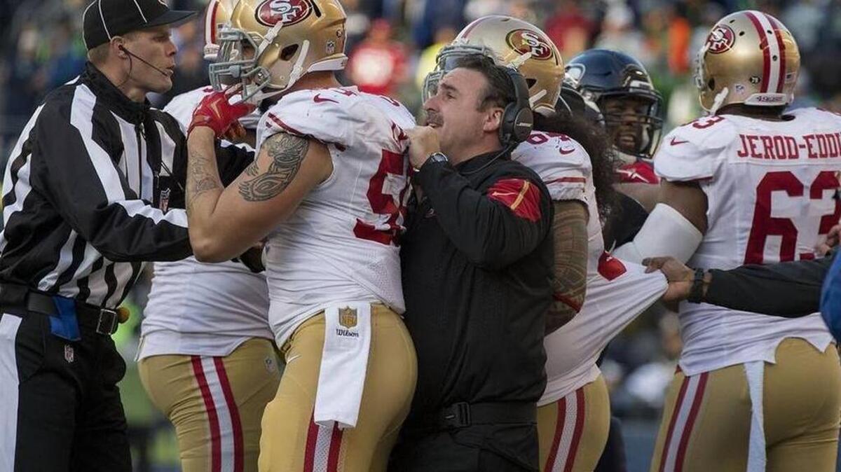 Jim Tomsula breaks up a scuffle in Seattle. The 49ers have allowed their opponents an average of 35.2 points per game in their five road trips this season.