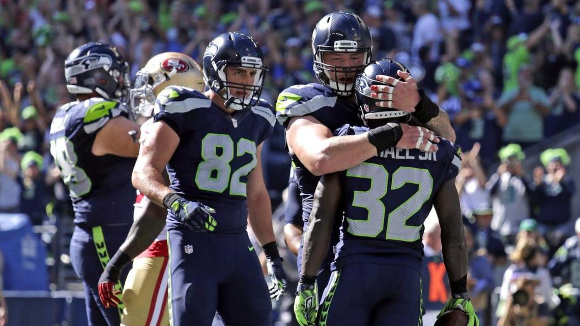 Seattle Seahawks' Christine Michael (32) is embraced by Justin Britt as Luke Willson (82) walks forward after Michael scored a touchdown against the San Francisco 49ers in the first half of an NFL football game, Sunday, Sept. 25, 2016, in Seattle.