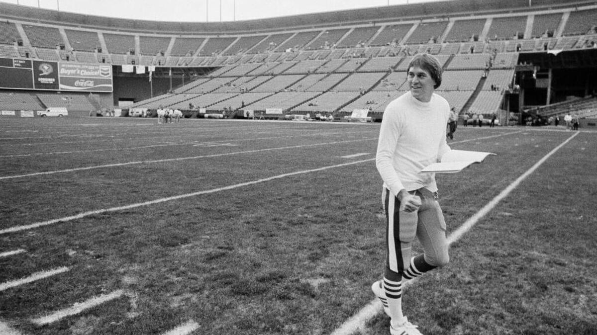 San Francisco 49ers receiver Dwight Clark, playbook in hand, walks the turf of Candlestick Park before the start of the Dallas Cowboys-49rers match-up in San Francisco.