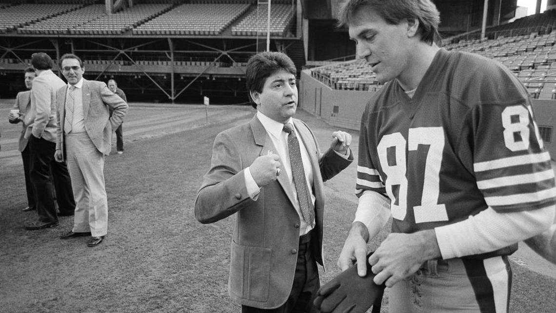 San Francisco 49ers wide receiver Dwight Clark (87) listens to a few words from 49ers owner Eddie De Bartolo Jr., before picture day in San Francisco, Jan. 16, 1985.