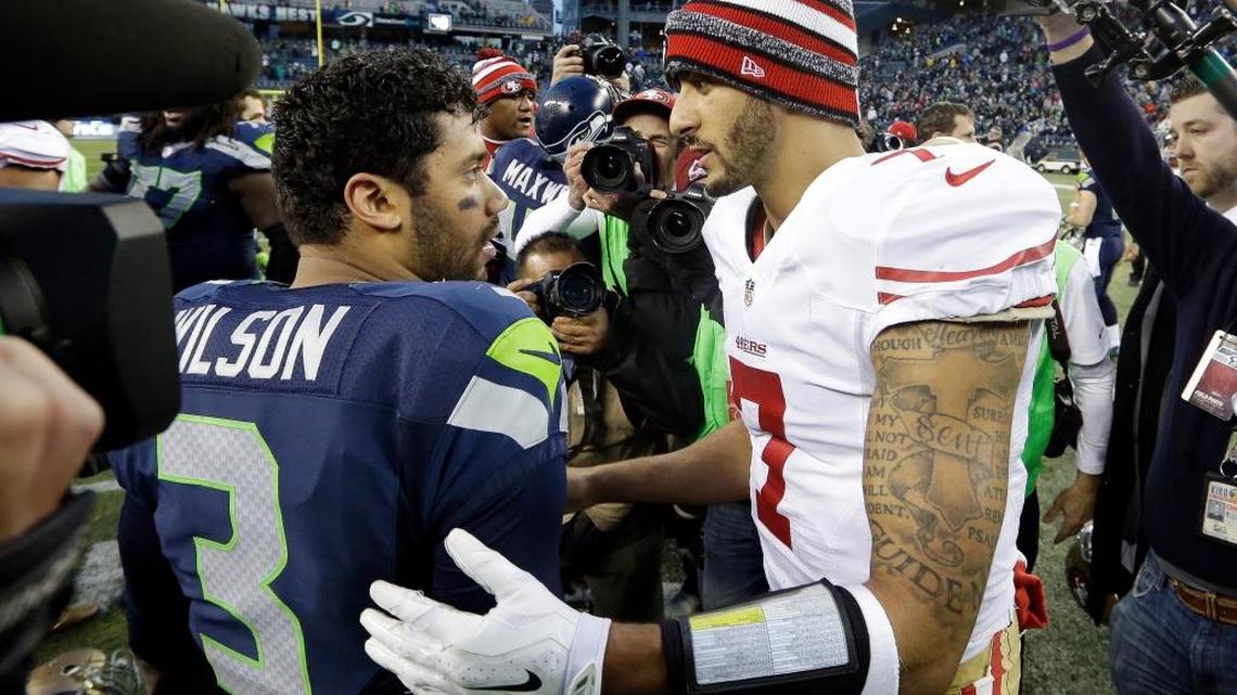 Seattle Seahawks quarterback Russell Wilson, left, and 49ers quarterback Colin Kaepernick meet after a game on Dec. 14, 2014, in Seattle. Kaepernick, who has been out of a job since March, could land with the 49ers’ division rivals.