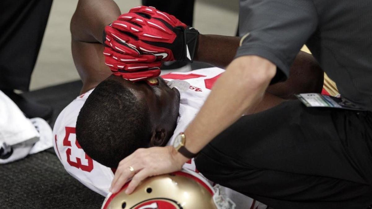San Francisco 49ers running back Reggie Bush is tended to by a trainer after he slipped out of bounds after running the ball during the first quarter of an NFL football game against the St. Louis Rams Sunday, Nov. 1, 2015, in St. Louis.