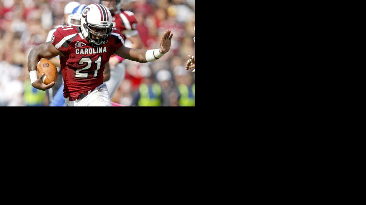 
South Carolina running back Marcus Lattimore (21) puts an arm up toward Kentucky linebacker Danny Trevathan (22) on a first down run during the third quarter in an NCAA college football game at Williams Brice Stadium on Saturday, Oct. 8, 2011, in Columbia, S.C. 

