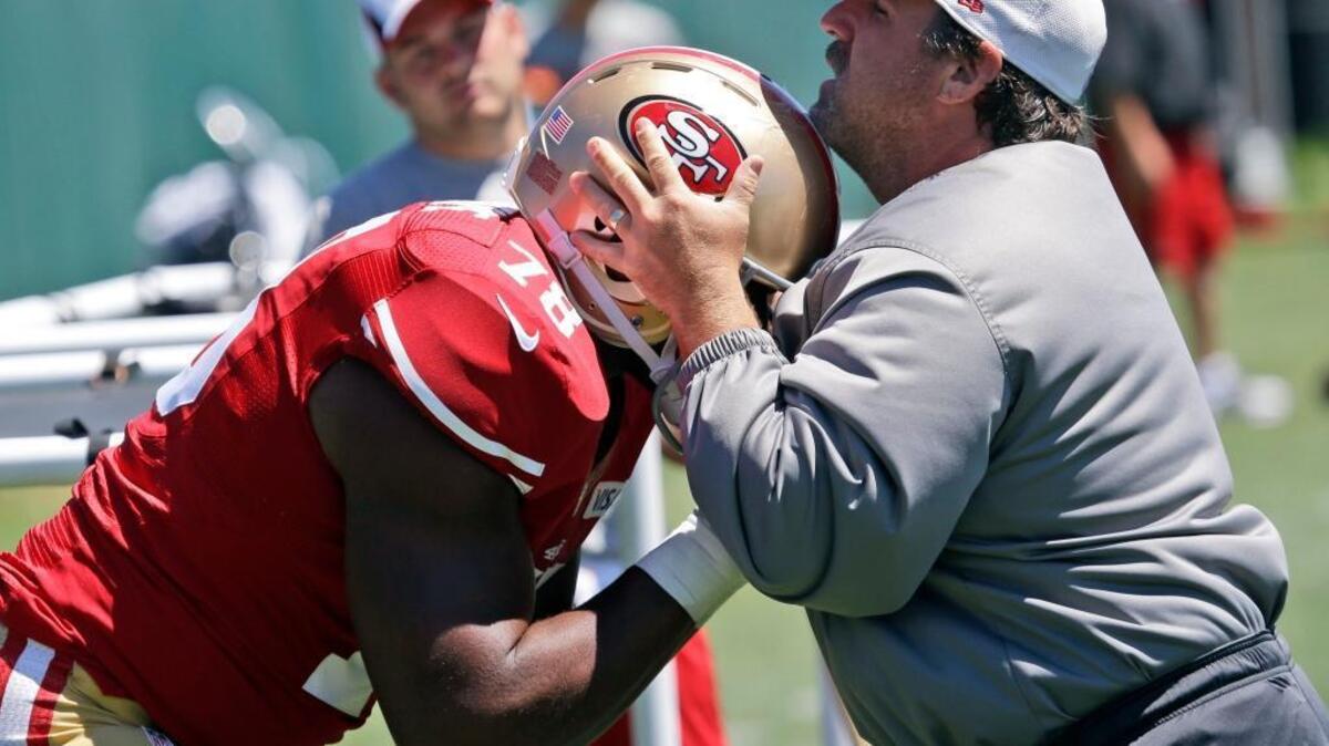 Then-defensive line coach Jim Tomsula, right, instructs San Francisco 49ers lineman Lawrence Okoye during camp on Thursday, Aug. 1, 2013, in Santa Clara, Calif.