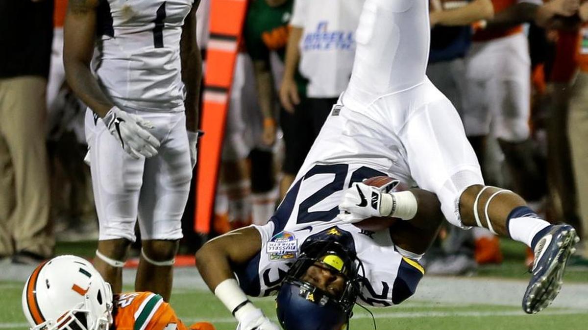 West Virginia running back Martell Pettaway, right, is upended by Miami defensive back Adrian Colbert (25) during the second half of the Russell Athletic Bowl NCAA college football game, Wednesday, Dec. 28, 2016, in Orlando, Fla. Miami won 31-14.