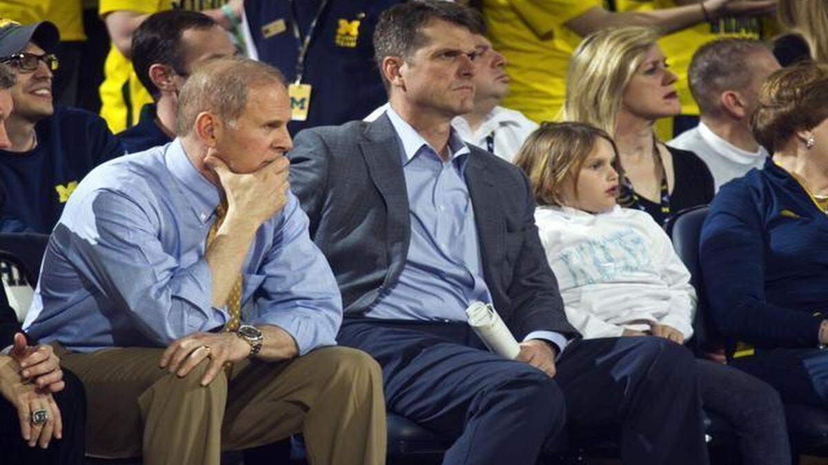 
Michigan head coach John Beilein, left, sits next to new Michigan football head coach Jim Harbaugh, center, in the first half of an NCAA basketball game against Michigan State at Crisler Center in Ann Arbor, Mich., Tuesday, Feb. 17, 2015.
