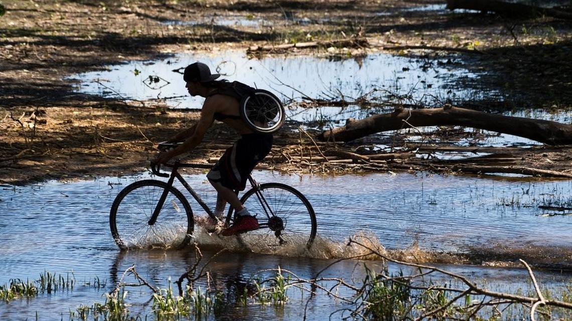 A cyclist rides through water covering the bike trail at Discovery Park on Monday May 1, 2017.