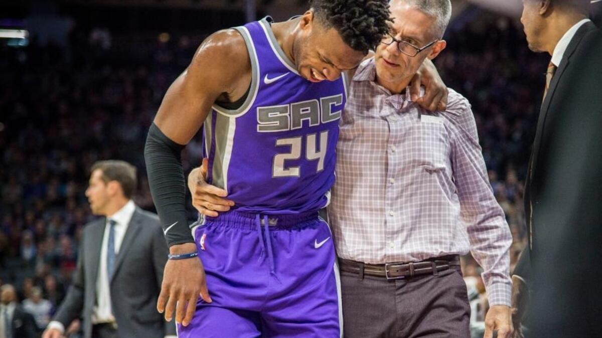 Kings guard Buddy Hield is helped off the court by trainer Pete Youngman on Friday in Sacramento.