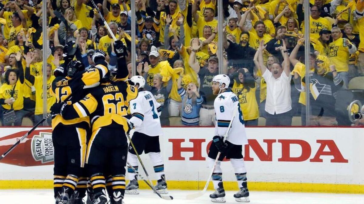 Pittsburgh Penguins Ben Lovejoy (12) and Carl Hagelin (62) swarm Nick Bonino after his game-winning goal against the San Jose Sharks during the third period in Game 1 of the Stanley Cup Final series Monday, May 30, 2016, in Pittsburgh. The Penguins won 3-2.
