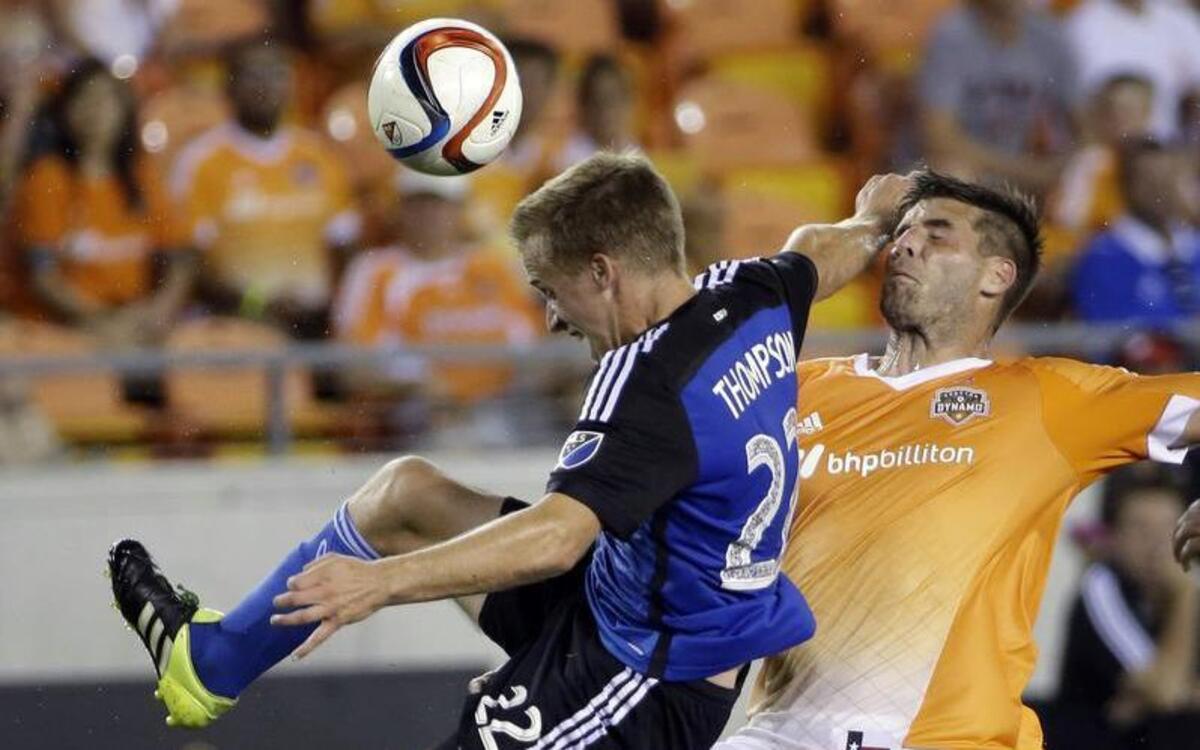 
San Jose Earthquakes' Tommy Thompson (22) is hit from behind by Houston Dynamo's David Horst (18) during the second half of an MLS soccer match Saturday, Aug. 8, 2015, in Houston. The Dynamo won 2-1.
