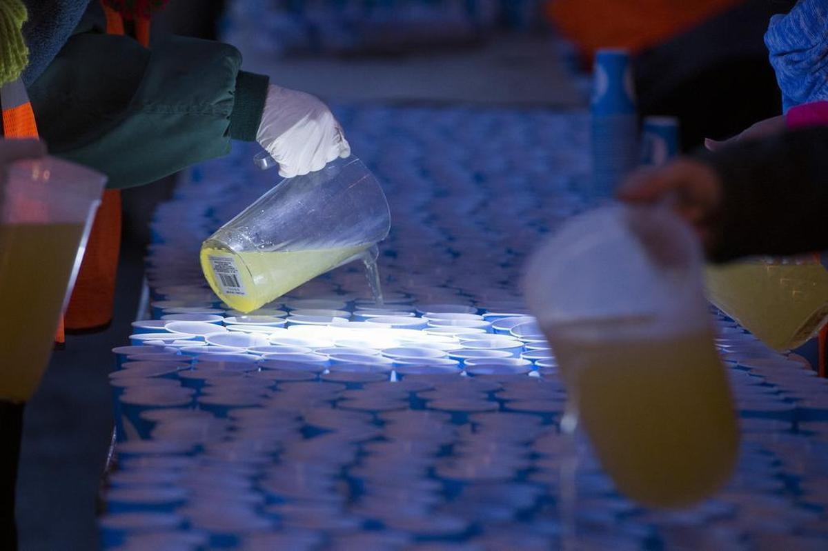 Volunteers fill water glass before the start of the California International Marathon in Fair Oaks in 2017.