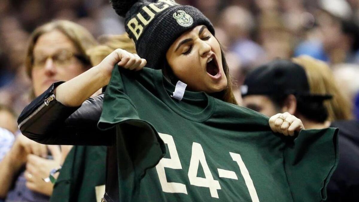 A fan cheers while holding up a “24-1” shirt during an NBA basketball game between the Milwaukee Bucks and the Golden State Warriors Saturday, Dec. 12, 2015, in Milwaukee. The Bucks won 108-95, ending the Warriors’ 24-game winning streak to start the season. Will the Warriors hand out 10-15 shirts Friday against the visiting Bucks, who improved to that record with the victory?